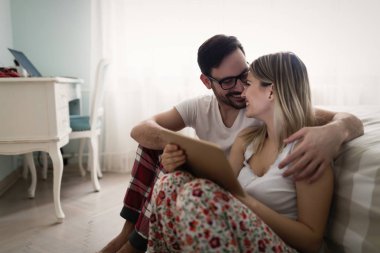 Genç çekici çift yatak odasında dijital tablet kullanma