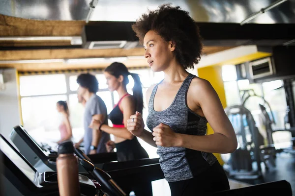 Fit happy people running in machine treadmill at fitness gym