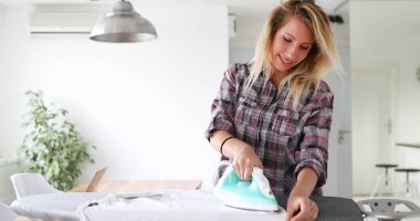 Güzel genç kadın giysileri evde Ütü ve satma ev işleri yaparak