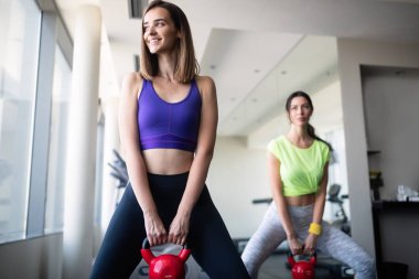 Spor salonunda dambıllarla çalışan çekici kadınlar..