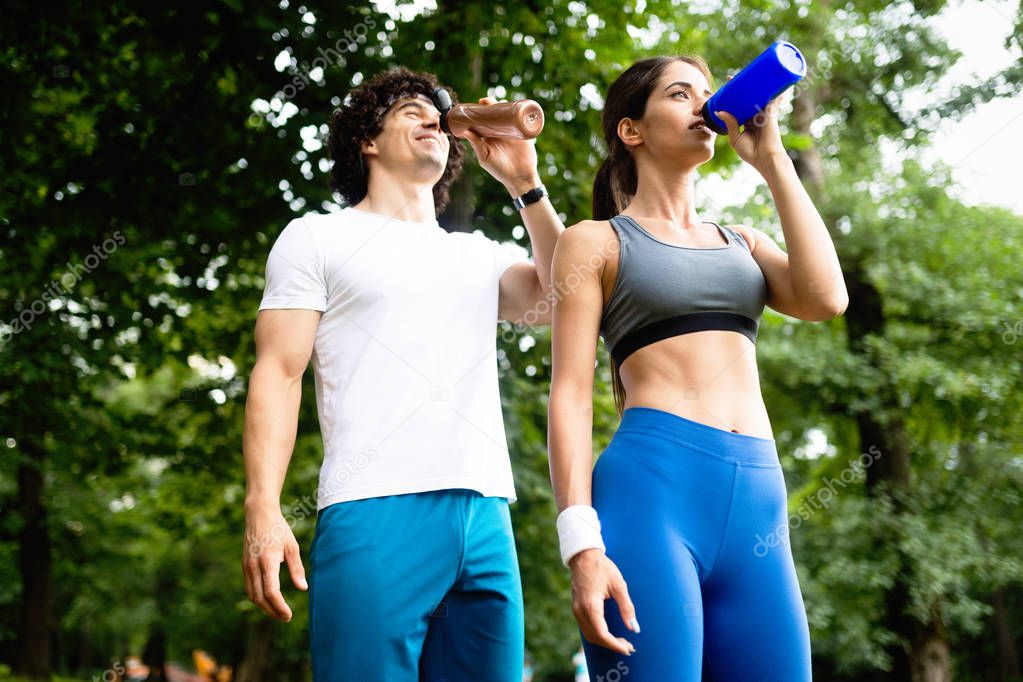Couple drinks water after running to replenish energy and to hydrate