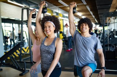 Spor salonunda egzersiz yapan bir grup genç.