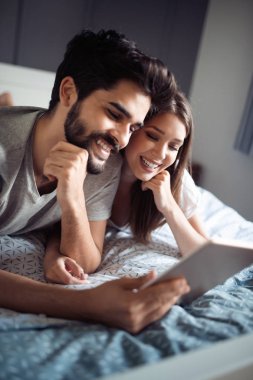 Mutlu çift aşık evde pijamayla tablet kullanma