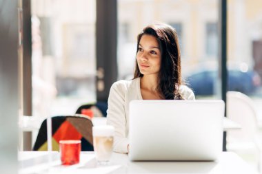 Güzel genç şirin esmer kafede dizüstü kullanarak