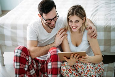 Genç mutlu çift yatak odasında dijital tablet kullanma