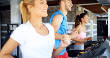 Genç çekici kadın spor salonunda ağırlık kaybı için kardiyo egzersizi yapıyor