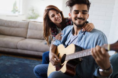 Genç yakışıklı adam güzel kız arkadaşı için gitar çalıyor.