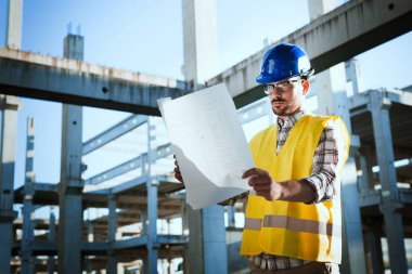 Genç iş adamı inşaat sitesi mühendis mavi baskı ile