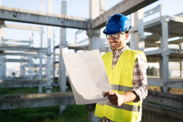 Engineers working on a building site holding a blue prints