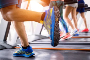 bir spor salonunda bir koşu bandı üzerinde çalışan insanlar. Spor ve sağlık kavramı