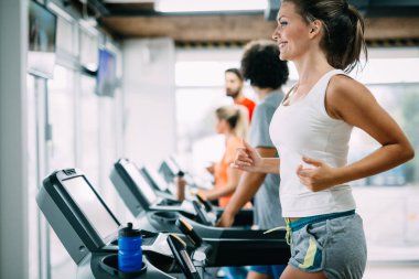 Spor salonunda koşu bandında egzersiz yapan bir grup arkadaş.