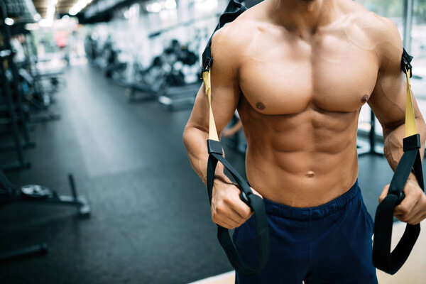 Young handsome strong man doing exercises in gym