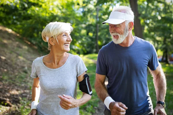 Healthy mature couple jogging in a park at early morning