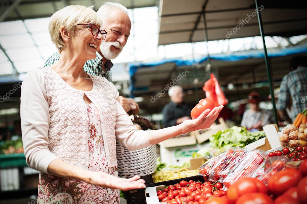 Senior couple buying fresh vegetables at the local market