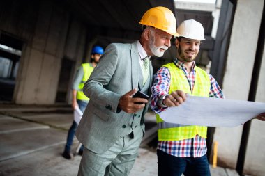 Mimarlar ve mühendislerden oluşan kendinden emin bir ekip modern inşaat alanında birlikte çalışıyor.