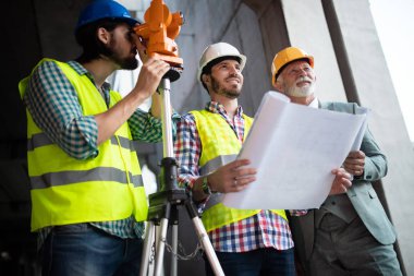 Mühendis, ustabaşı ve işçi inşaat alanında tartışıyor ve çalışıyor.