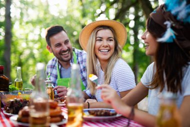 Açık havada barbekü akşam yemeği bira içme ve yemek yeme mutlu arkadaş grubu