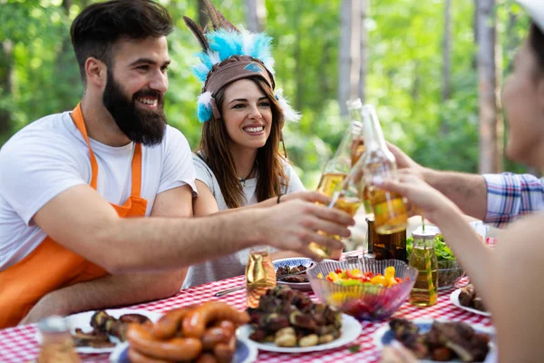 食べるとバーベキュー ディナーを屋外でビールを飲んで幸せな友人のグループ — ストック写真