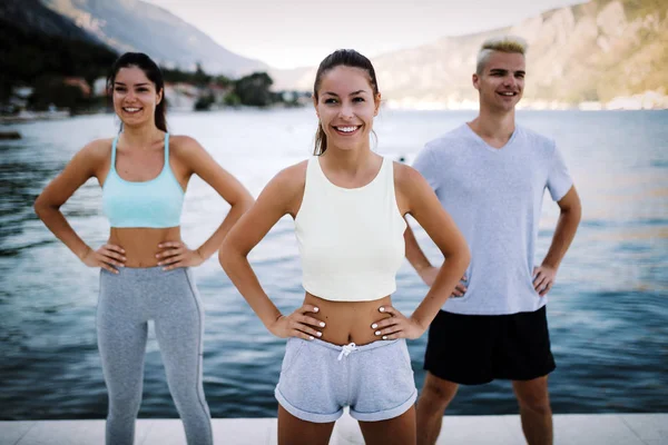 Fitness, sport, friendship and healthy lifestyle concept. Group of happy friends or sportsmen exercising and stretching outdoor