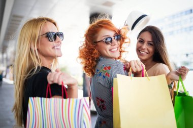 Gülen ve having fun birlikte alışveriş yaparken mutlu genç kadın arkadaşlar