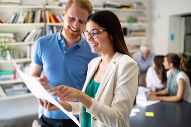 Ofiste iş arkadaşlarıyla birlikte çalışan ve iletişim kuran bir grup iş adamı.