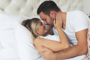 Mutlu genç çift yatak odasında romantik anlar yaşıyor.