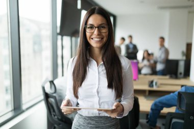 Modern ofiste dijital tablet kullanan çekici bir iş kadını