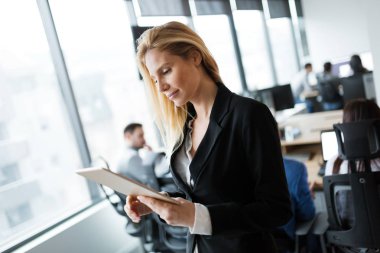 Modern ofiste dijital tablet kullanan çekici bir iş kadını