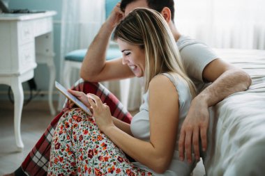 Genç mutlu çift yatak odasında dijital tablet kullanma