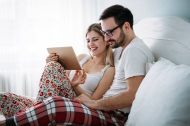 Genç mutlu çift yatak odasında dijital tablet kullanma