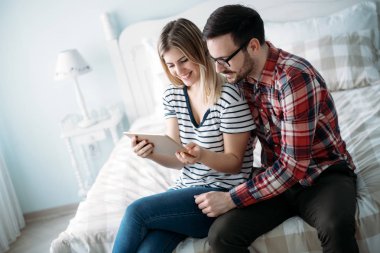 Genç mutlu çift yatak odasında dijital tablet kullanma
