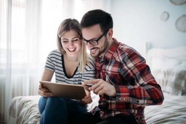 Genç mutlu çift yatak odasında dijital tablet kullanma