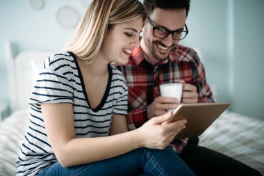 Genç mutlu çift yatak odasında dijital tablet kullanma