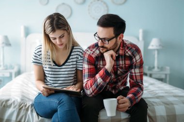 Genç mutlu çift yatak odasında dijital tablet kullanma