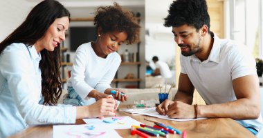 Anne ve baba evde çocuklarıyla birlikte resim çiziyorlar.