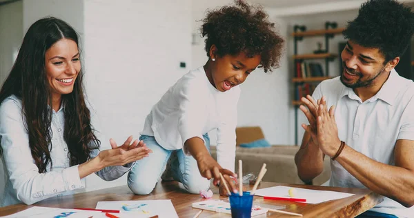 Mom and dad drawing with their daughter at home