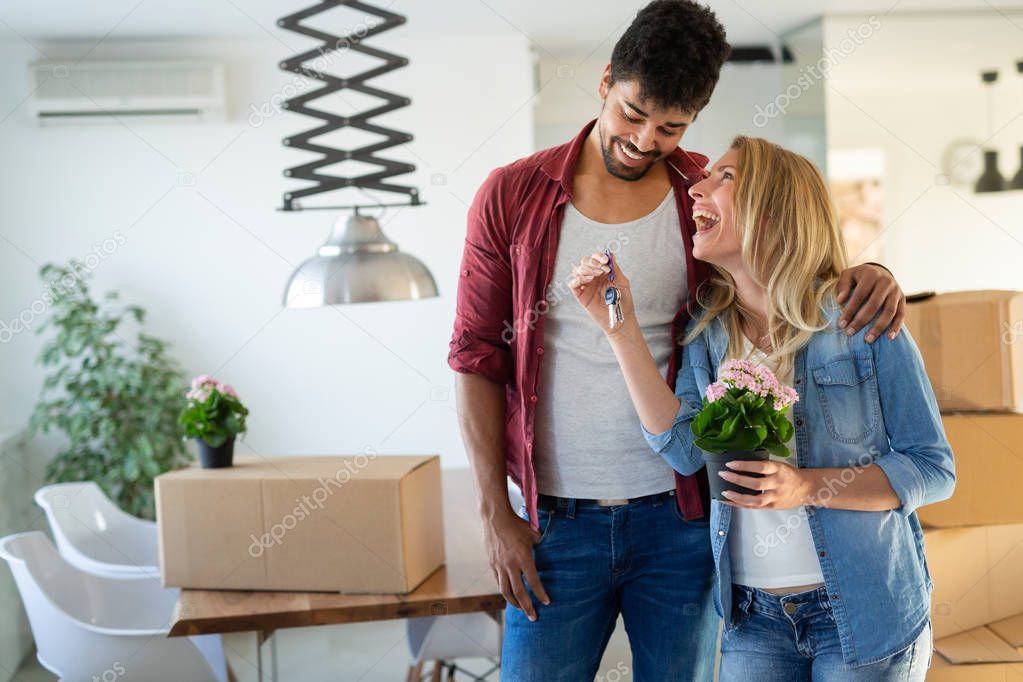 Young happy couple in love moving in new home and unpacking boxes