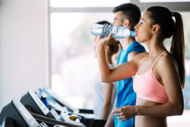 Spor salonunda koşu bandında kardiyo antrenmanı yapan insanların fotoğrafı.