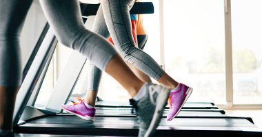 Spor salonunda koşu bandında kardiyo antrenmanı yapan insanların fotoğrafı.