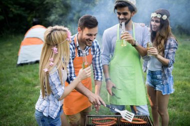 Neşeli arkadaşlar doğada vakit geçirip barbekü yapıyorlar.