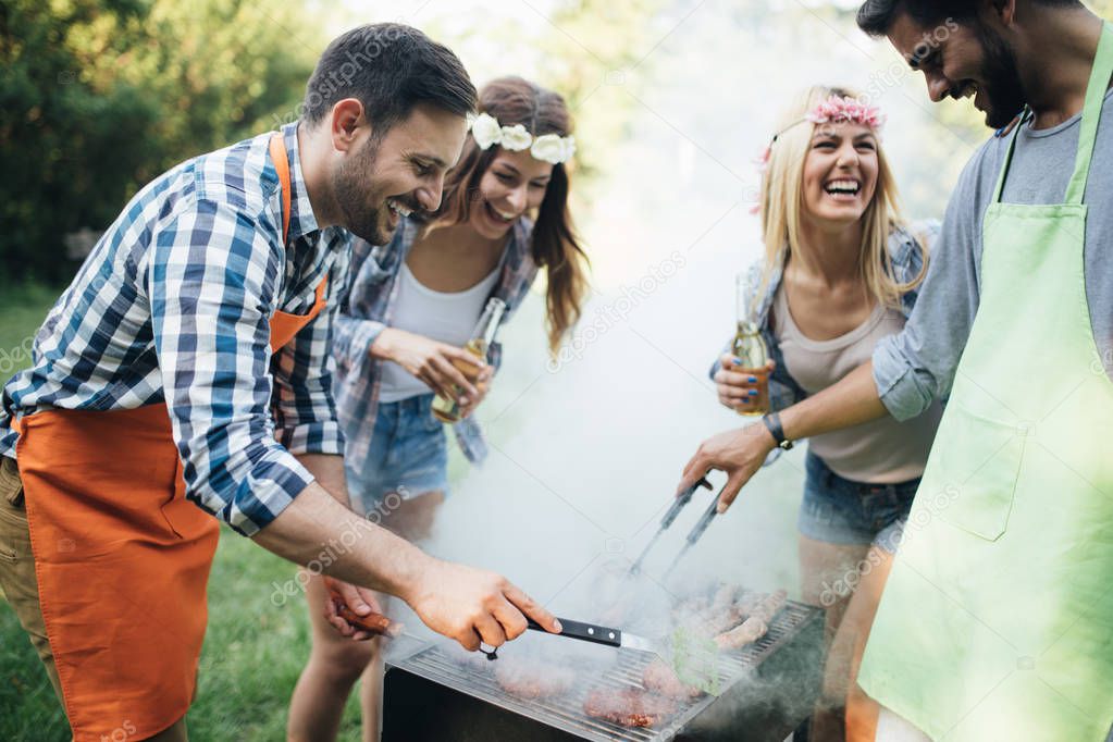 Cheerful friends spending time in nature and having barbecue