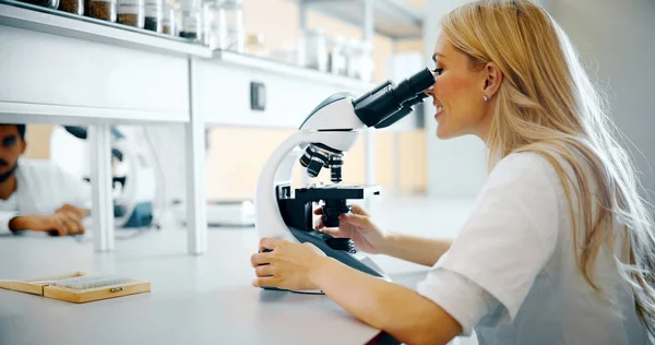 Νεαρή Γυναίκα Επιστήμονας Κοιτάζοντας Μέσα Από Μικροσκόπιο Στο Εργαστήριο — Φωτογραφία Αρχείου