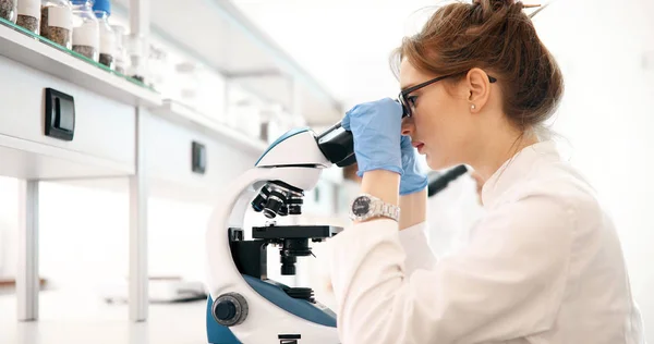 研究室で顕微鏡を見ている若い女性科学者 — ストック写真