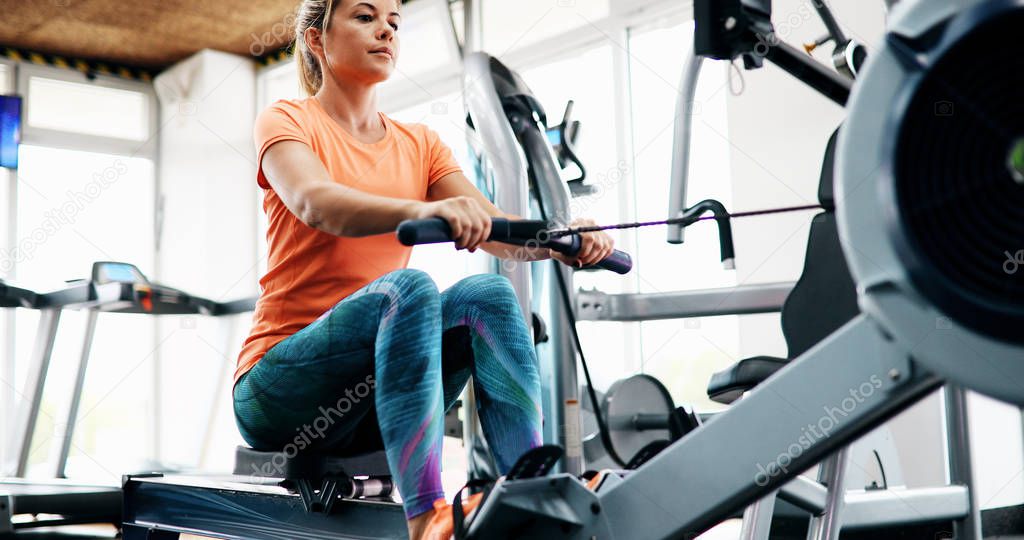 Workout woman cross training exercising cardio using rowing machine in fitness gym