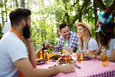 Açık havada barbekü akşam yemeği bira içme ve yemek yeme mutlu arkadaş grubu