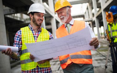 Mühendis, ustabaşı ve işçi inşaat alanında tartışıyor ve çalışıyor.