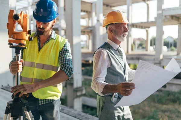 Team av arkitekter och ingenjörer i grupp på byggarbetsplatsen kontrollera dokument och arbetsflöde — Stockfoto