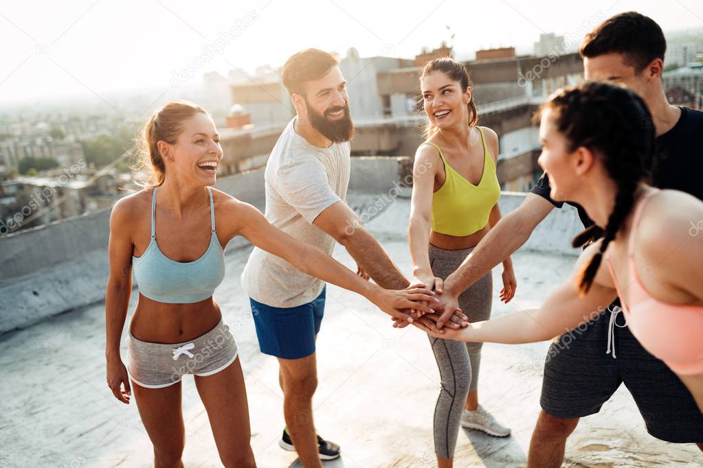 Group of happy fit young people friends training outdoors at sunrise