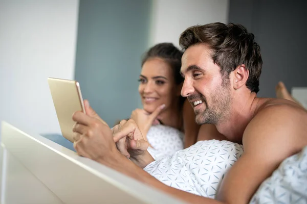 Casal Alegre Olhando Tablet Juntos Rindo Enquanto Deitado Cama — Fotografia de Stock