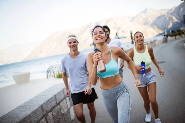 Group of happy young people friends running outdoors at seaside